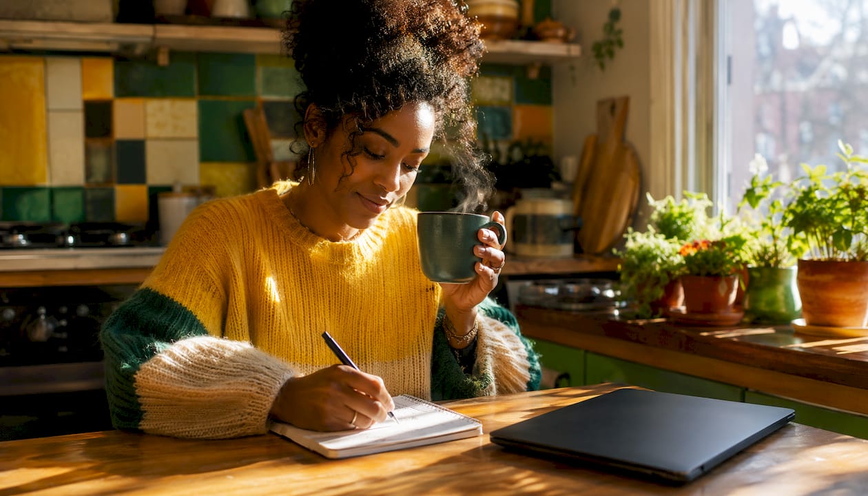Woman sipping specialty coffee while writing notes